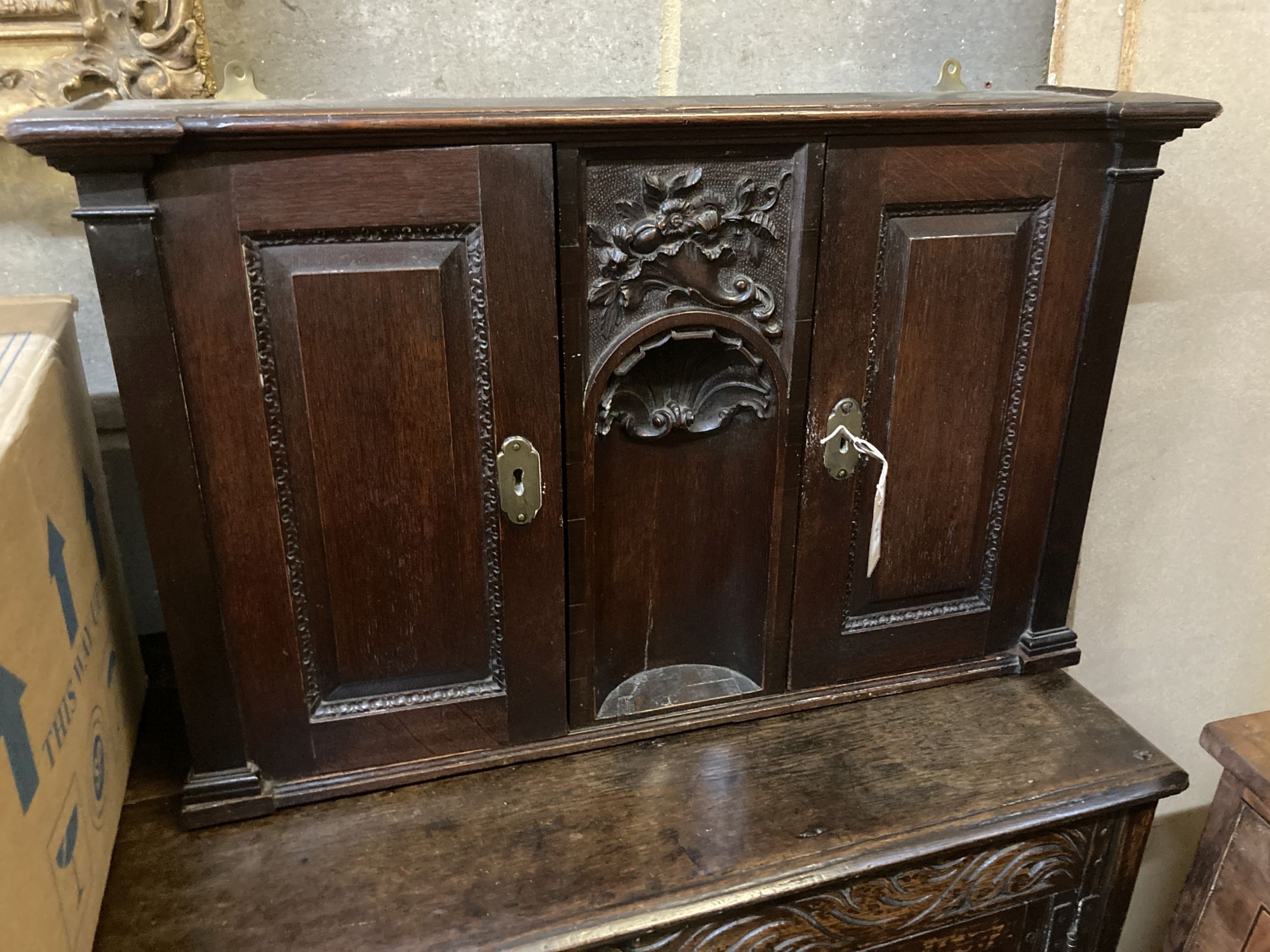 An 18th century style carved oak two door wall cabinet, with concealed central compartment, width 80cm, depth 19cm, height 50cm